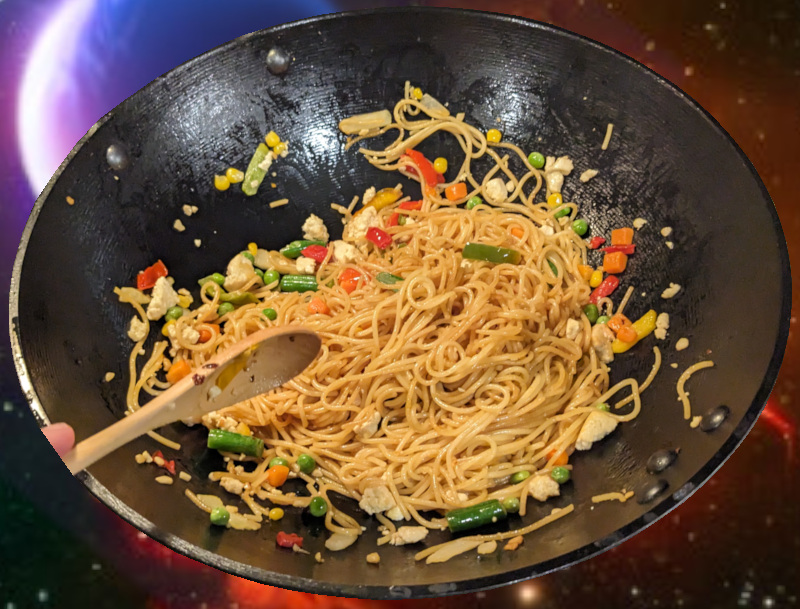 A wok full of fried noodles with some veggies and tofu chunks.
